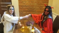 Osoby przebrane za anioła i diabła ściskają sobie dłonie