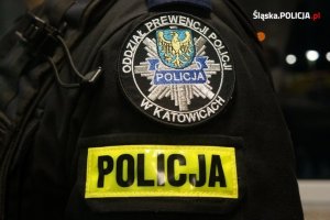 rękaw munduru ćwiczebnego z logo Oddziału Prewencji Policji w Katowicach oraz naszywką z napisem Policja na żółtym tle