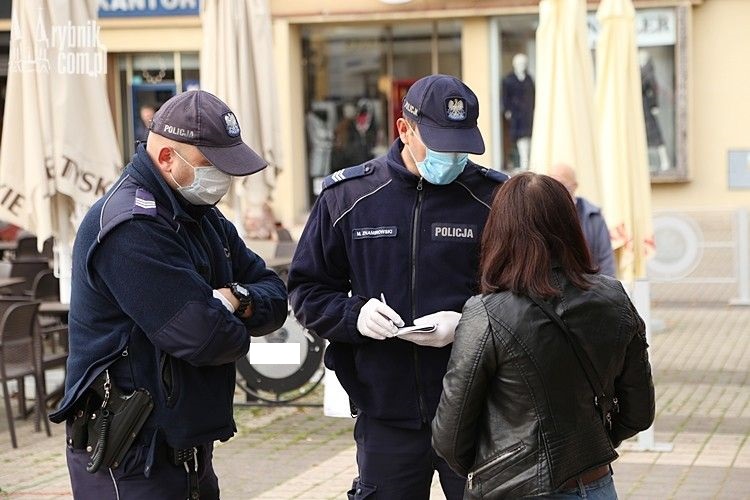 Policjanci w maseczkach rozmawiają z kobietą.