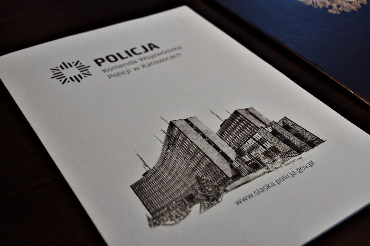 Kolorowe zdjęcie. Teczka z logo Komendy Wojewódzkiej Policji w Katowicach, w której znajduje się rozkaz dla awansowanego policjanta.