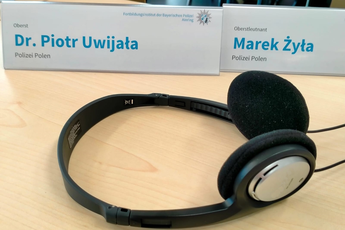 Zdjęcie słuchawek leżących na stole przy tabliczkach z nazwiskami uczestników konferencji 