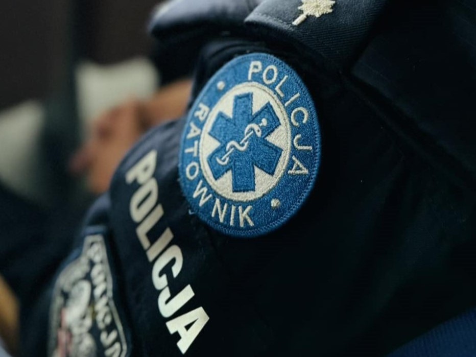 Na zdjęciu zbliżenie na ramię policjanta na którym widać naszywkę z napisem Policja Ratownik, poniżej napis Policja. 