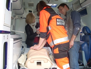 Ratownik medyczny ćwiczy na manekinie wewnątrz karetki pogotowia w obecności dziennikarza