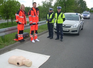 Ratownicy medyczni w obecności policjantów przed matą z fantomem do ćwiczeń