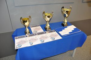 Zdjęcie kolorowe, przedstawiające nagrody w postaci dyplomów oraz pucharów dla zwycięzców konkursu