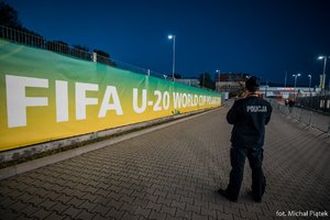 policjant na chodniku, ogrodzenie stadionu i widoczny napis FIFA U 20