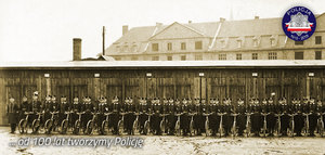 Zdjęcie archiwalne z okresu międzywojennego: oddział policjantów z rowerami w szeregu przed jednostką