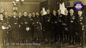 Zdjęcie archiwalne z okresu międzywojennego: grupa policjantów w strojach galowych wewnątrz budynku