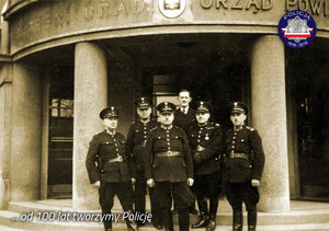 Zdjęcie archiwalne z okresu międzywojennego: grupa policjantów przed budynkiem urzędowym