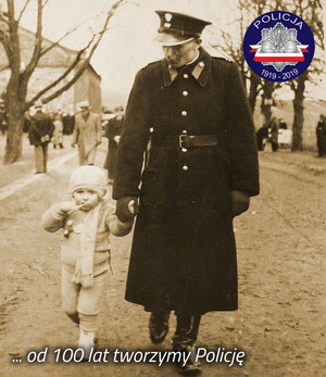 Zdjęcie archiwalne z okresu międzywojennego: policjant prowadzi dziecko za rękę