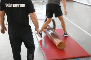 mężczyzna- instruktor patrzy na ćwiczącego mężczyznę który podnosi manekina z podłogi