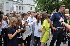 Roksana Węgiel pozuje do zdjęć z uczniami, w tle policjant ze śląskiej drogówki oraz dziennikarze, którzy przybyli na spotkanie