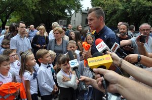 policjant śląskiej drogówki przekazuje dzieciom najważniejsze zasady dotyczące bezpieczeństwa, w tle dziennikarze