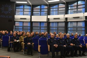policjanci siedzący w auli, w której odbyła się odprawa; pierwsze miejsca zajmuje Komendant Wojewódzki Policji w Katowicach wraz ze swoimi zastępcami
