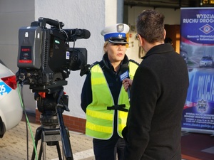 Na zdjęciu umundurowana policjantka udziela wywiadu dziennikarzowi stacji telewizyjnej w czasie akcji &quot;twoje Światła - Nasze Bezpieczeństwo&quot;.