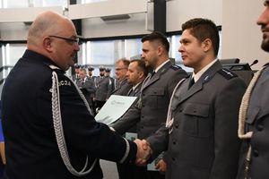 Zdjęcie kolorowe. Komendant Wojewódzki Policji w Katowicach nadinspektor dr Krzysztof Justyński gratuluje policjantowi