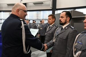 Zdjęcie kolorowe. Komendant Wojewódzki Policji w Katowicach nadinspektor dr Krzysztof Justyński gratuluje policjantowi