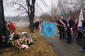 Zdjęcie kolorowe. Widoczna warta honorowa pod pomnikiem, sztandar oraz osoby oddające hołd tragicznie zmarłym