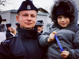 Policjant trzyma na ręku dziecko.