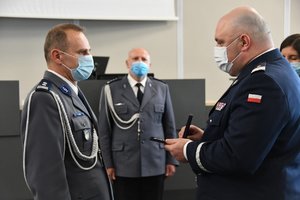 Zdjęcie kolorowe. Komendant Wojewódzki Policji wręcza odznakę zasłużony policjant