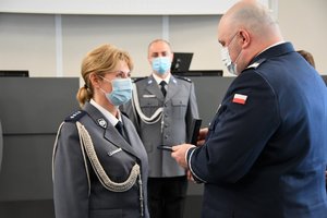 Zdjęcie kolorowe. Komendant Wojewódzki Policji wręcza odznakę zasłużony policjant