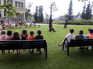 Policyjny przewodnik wraz z psem oraz policjantka opowiadają dzieciom o bezpiecznych wakacjach