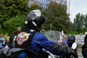 Motocyklista na motocyklu, w tle budynek Komendy Wojewódzkiej Policji w Katowicach.