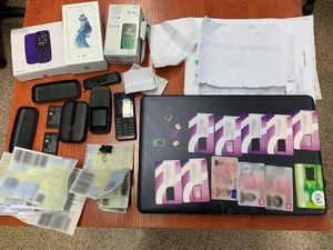Zdjęcie kolorowe. Telefony, karty sim i dokumenty zabezpieczone przez policjantów.