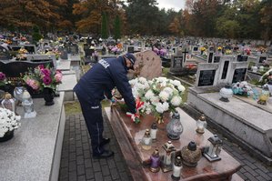 Zdjęcie kolorowe. Widoczny grób śp. sierż. Grzegorza Załogi podczas składania kwiatów przez policjantów i bliskich