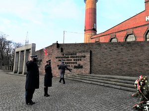 Policjanci oddają honor przed pomnikiem upamiętniającym poległych górników w kopalni Wujek.