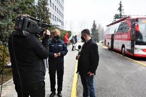 Rzecznik Komendanta Wojewódzkiego Policji w Katowicach udziela wywiadu dla telewizji. W tle autobus, w którym pobierana jest krew oraz osoby, które oczekują, by wejść do środka.