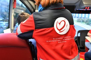 Zdjęcie przedstawia plecy kobiety, która ma na sobie polar z napisem: Regionalne Centrum Krwiodawstwa i Krwiolecznictwa Katowice. Nad napisem logo centrum.