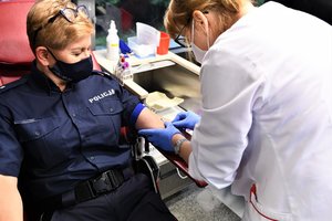Pielęgniarka wkłuwa igłę w rękę policjantki, która odda krew.