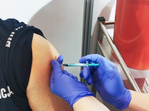 Zdjęcie przedstawia moment podawania szczepionki - wkłucia igły w ramię.