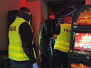 trzech policjantów w salonie gier hazardowych i widoczny automat do gry.