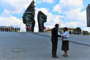 Prezydent wręcza kobiecie Order Orła Białego, który został pośmiertnie nadany Alfonsowi Zgrzebniokowi. W tle Pomnik Powstańców Śląskich.