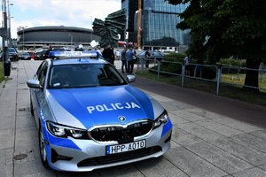 Policjanci w radiowozie dbają, by nie doszło do zakłócenia uroczystości. W tle Pomnik Powstańców Śląskich.