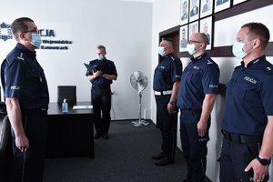 Awansowani policjanci stoją naprzeciwko Komendanta Wojewódzkiego Policji w Katowicach podczas uroczystości. W tle Naczelnik Wydziału Kadr.