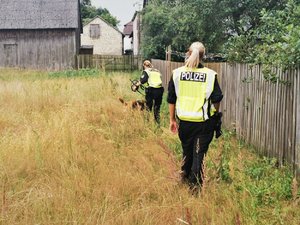 Zdjęcie kolorowe. Widoczne umundurowane policjantki niemieckie wraz z psem służbowym