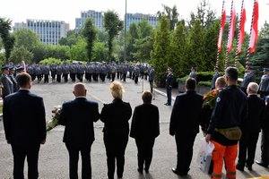 Zdjęcie kolorowe. Widoczni umundurowani policjanci oraz osoby cywilne biorący udział w uroczystości przed budynkiem komendy wojewódzkiej policji