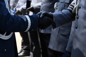 Zbliżenie na uścisk dłoni generała z wyróżnionym policjantem.