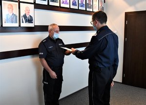 Kolorowe zdjęcie. Komendant Wojewódzki Policji w Katowicach wręcza awansowanemu policjantowi rozkaz.