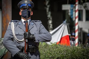 Policjant kompanii honorowej, a w tle flaga Polski