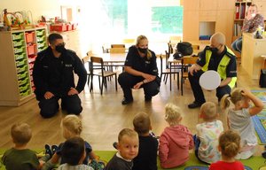 Policjanci w przedszkolu rozmawiają z dziećmi.