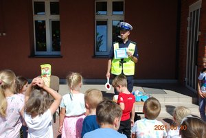 Policjant tłumaczy dzieciom zasady ruchu drogowego.
