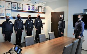Zdjęcie kolorowe: czterech umundurowanych policjantów stoi w szeregu, obok widocznych dwóch policjantów