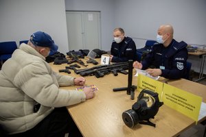 Policjanci przyjmujący rezerwistę w punkcie wydawania broni