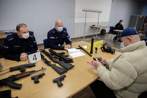 Policjanci przyjmujący rezerwistę w punkcie wydawania broni