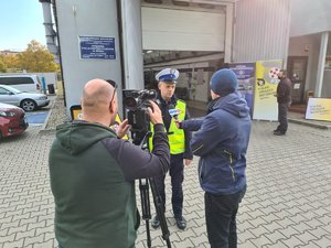 Policjant ruchu drogowego udziela wywiadu do telewizji przed stacją kontroli pojazdów