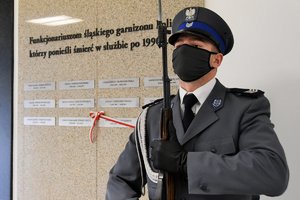 Policjant z Kompani Honorowej stoi przy Tablicy Pamięci.
